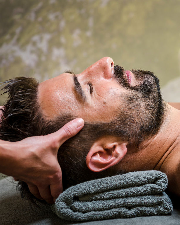 Nahaufnahme von Mann auf Behandlungsliege bei Kopfmassage im 4-Sterne-Luxushotel Hüttenhof