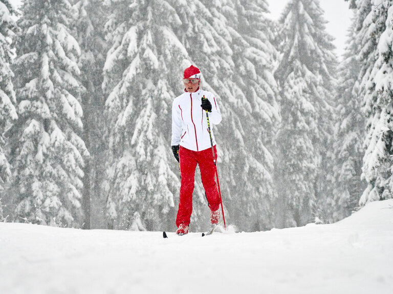 Langläufer mit roter Hose gleitet durch den schneebedeckten Bayerischen Wald