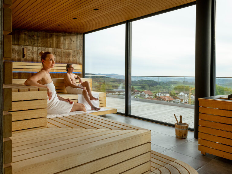 Paar sitzt in moderner Panoramasauna vom Wellnesshotel-Hotel Hüttenhof