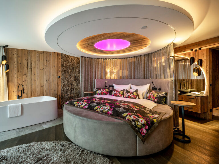 Stilvolles rundes Bett mit verstellbaren Vorhängen und moderner Deckenleuchte im Hotel Hüttenhof