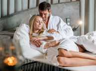 Pärchen genießt Wellnessurlaub im Bett im Luxus Chalet Bayerischer Wald