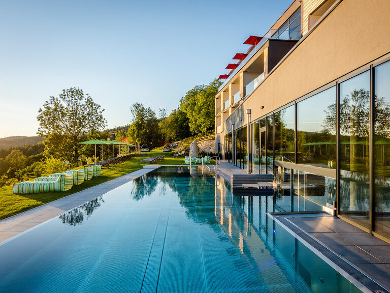 Moderner Außenpool vor Hotel Hüttenhof mit Garten und Liegen