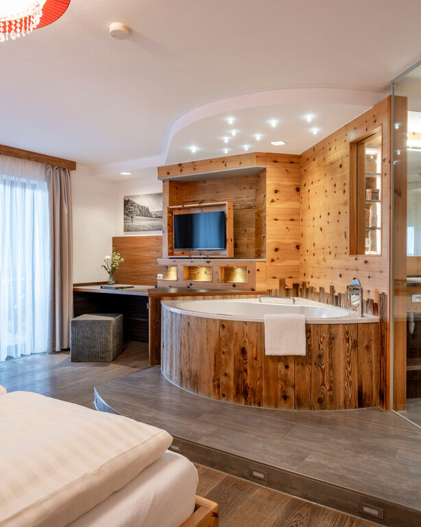 Einblick in Bad und Wohnbereich von modernem Zimmer mit Holzelementen und Whirlpool