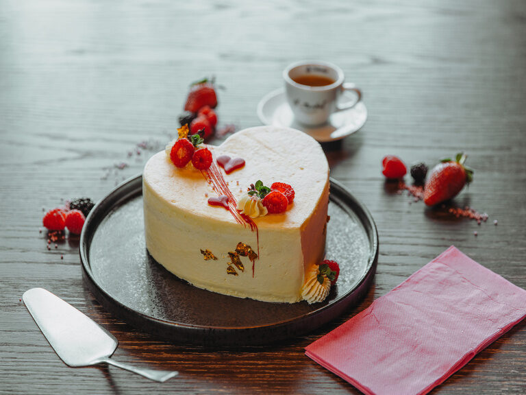 Befüllte Badewanne vor Kamin, mit Rosenblättern, darauf Holzbrett mit runden Badebomben