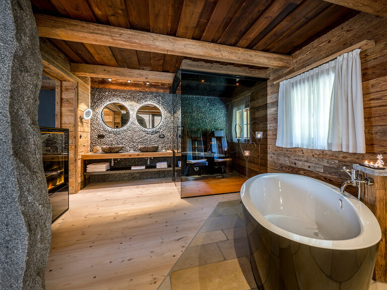 Badezimmer Chalet Bergdorf Hüttenhof Badezimmer mit freistehender Badewanne, Sauna und modernen Waschbecken