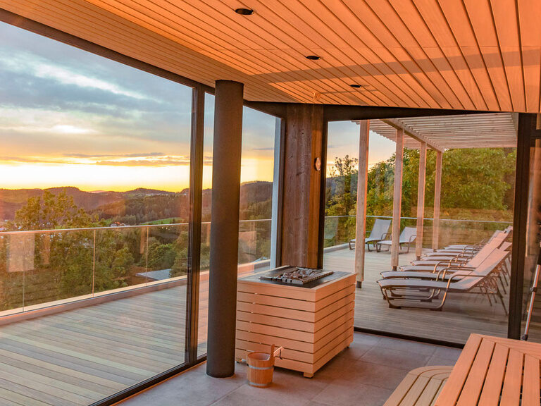 Blick aus Glaswänden von modernen Panoramasauna auf Bayerischen Wald bei Sonnenuntergang