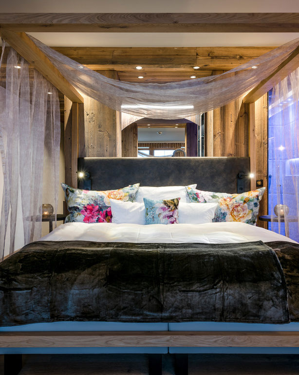 Modernes Himmelbett im Holzrahmen mit Blumenkissen in Luxus-Zimmer mit TV und Holzwänden