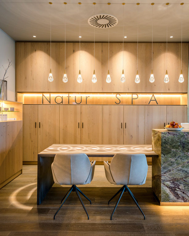 Moderner Beratungsraum mit Schriftzug 'Natur-SPA', Beleuchtung und Holzregal mit Pflege-Produkten