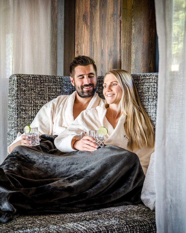 Paar entspannt auf einer Sofa-Liege und genießt Erfrischungsgetränke im 4-Sterne-Hotel Hüttenhof