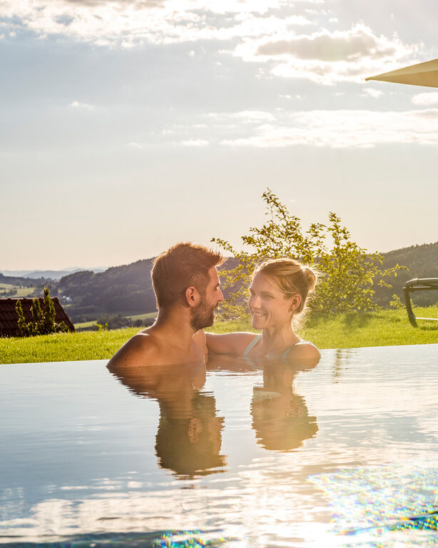 Verliebtes Pärchen schaut sich in die Augen im Infinity-Außenpool des 4 Sterne Wellnesshotel Hüttenhof im Bayerischen Wald