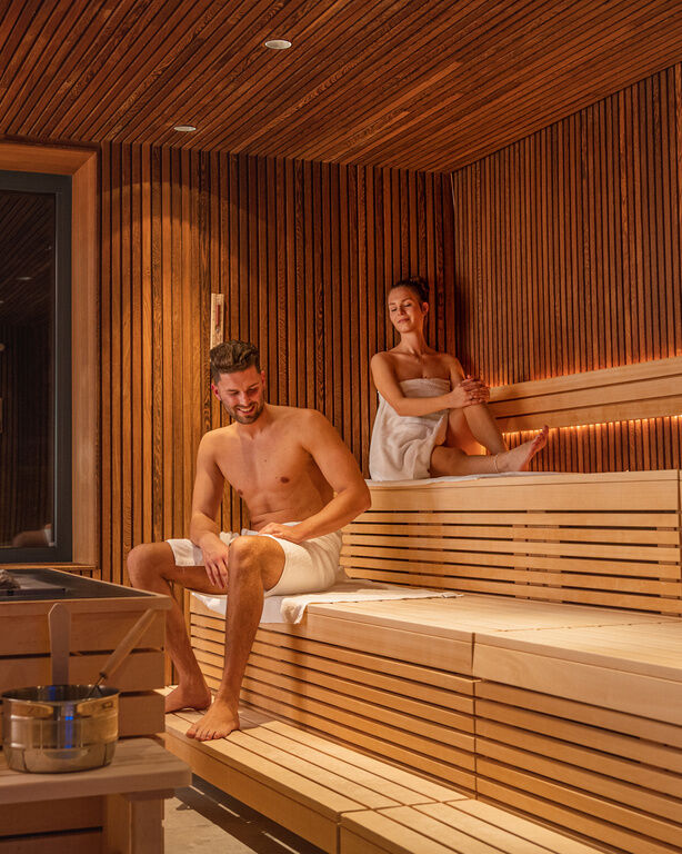 Sitzendes Pärchen auf einem Badetuch in der Sauna des 4 Sterne Luxushotel Hüttenhof im Bayerischen Wald