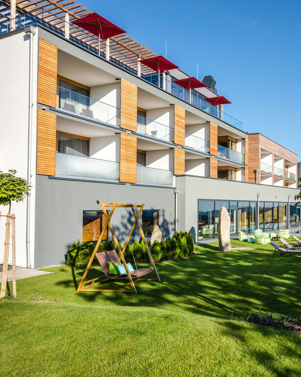 Außenaufnahme Hotel Hüttenhof mit Liegen auf Wiese und Außenpool an sonnigem Tag