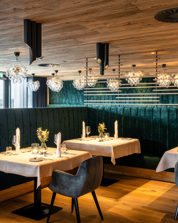 Elegantes Restaurant mit Kronleuchter und grüner Samtbank im Hotel Hüttenhof
