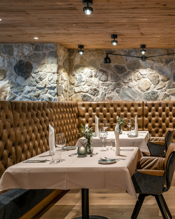 Modernes Restaurant mit braunen Sitz-Lederbänken und Steinwand