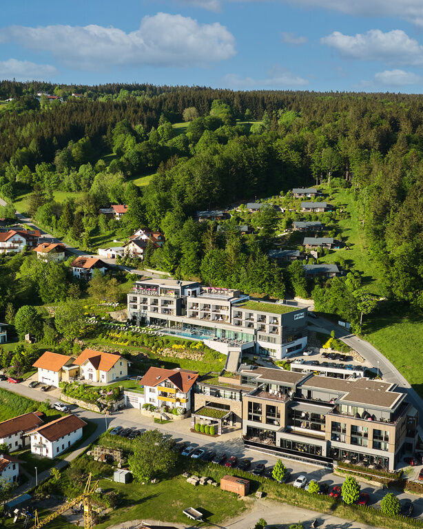 Das Hotel von oben, ganz oben im Wald das Bergdorf, etwas weiter unten das Hotel mit Außenpools und teilweise begrünten Dachflächen