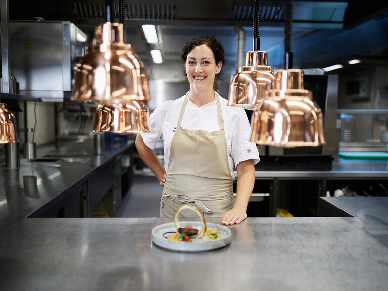 Köchin präsentiert ein exotisches Gericht Theke der Küche mit rosé goldenen Lampen