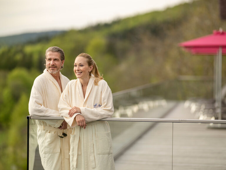 Lachendes Paar genießt den Ausblick vom Balkon der Terrasse im Luxushotel Hüttenhof
