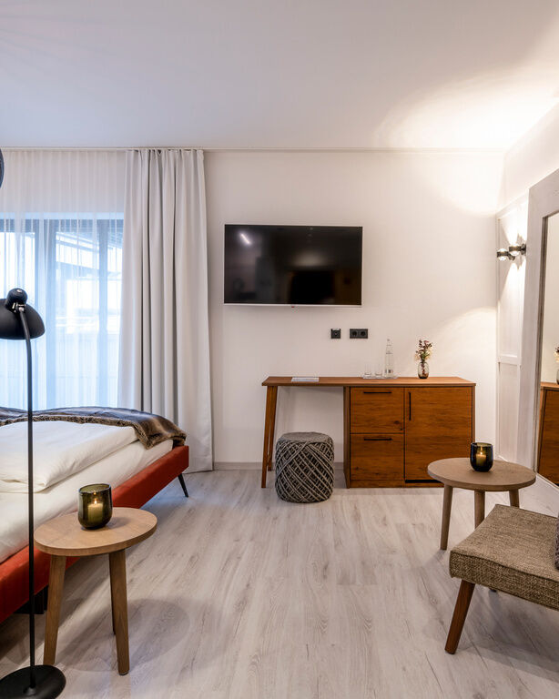 Modernes, helles Zimmer mit großem Bett, Sitzgelegenheiten und einem großen Fernseher