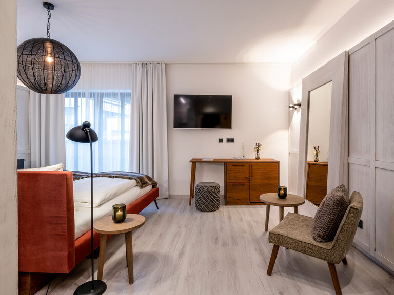 Modernes Hotelzimmer im Hüttenhof mit Flachbild-TV, Doppelbett und großem Spiegel