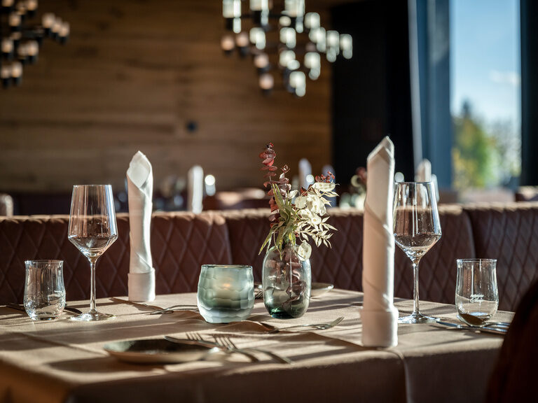 Eingedeckter Tisch im Restaurant im 4-Sterne-Luxushotel Hüttenhof Eingedeckter Tisch mit Kerzen-Servietten im 4-Sterne-Luxushotel Hüttenhof