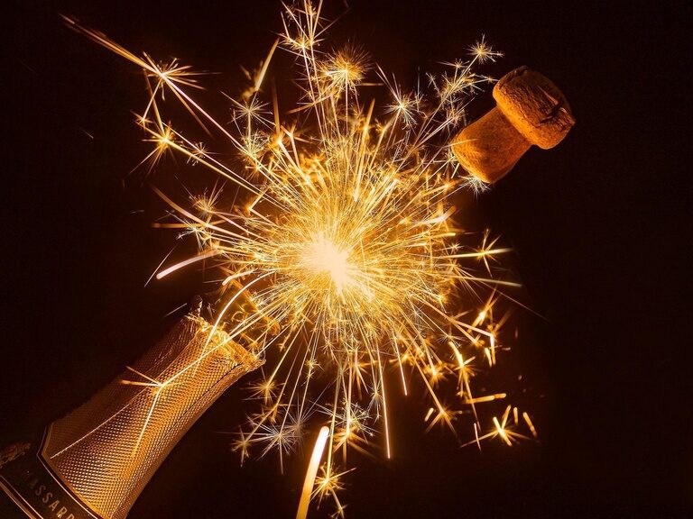 Flasche Sekt mit geöffnetem fliegenden Korken und Wunderkerze Flasche Sekt mit geöffnetem fliegendem Korken und Wunderkerze