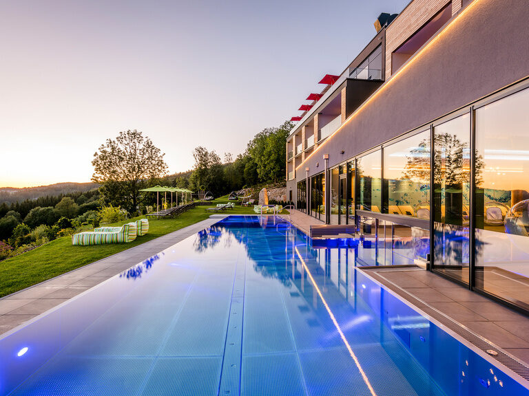 Ganzjährig beheizter Infinity-Außenpool mit zahlreichen Liegemöglichkeiten des 4 Sterne Luxushotel Hüttenhof im Bayerischen Wald