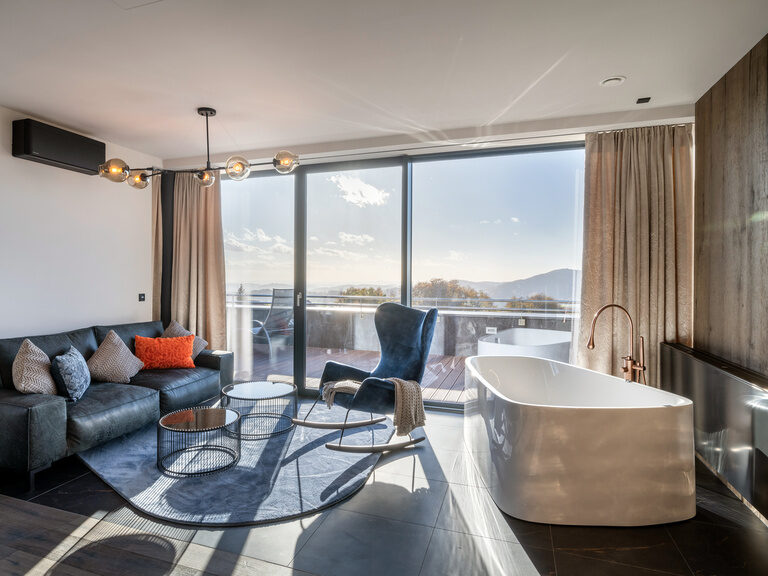 Gemütliches Sofa und Schaukelstuhl mit freistehender Badewanne des 4 Sterne Luxushotel Hüttenhof in Bayern