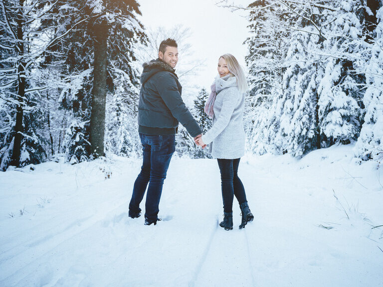 Glückliches Paar küsst sich auf Sofa in Holzhütte nahe dem Wellnesshotel Hüttenhof Liebespaar, küsst sich liebevoll auf gemütlichen Sofa in rustikalen Holz-Hütte