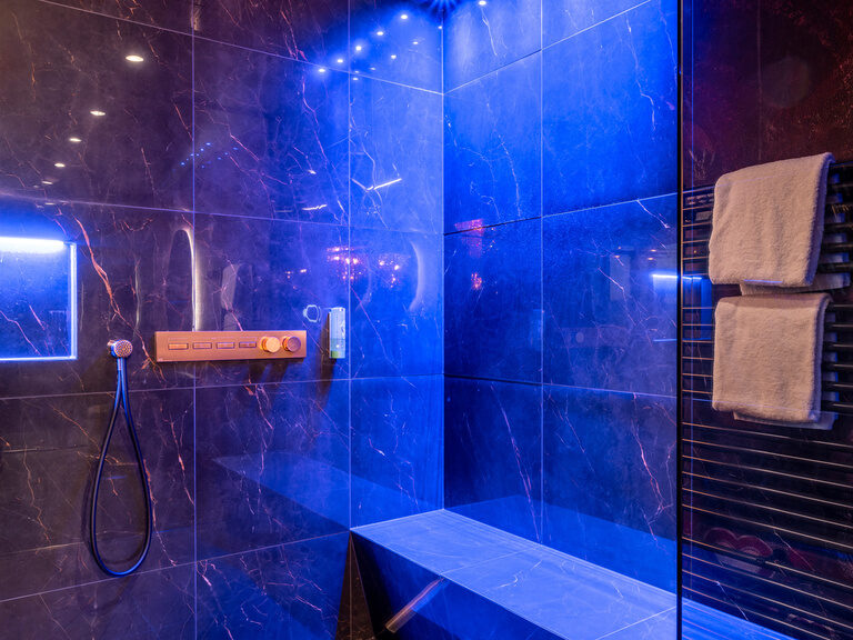 Goldener Kamin und Hängematte in moderner Luxussuite im Hotel Hüttenhof Goldener, glänzender Kamin, Hängematte, Kronleuchter und modernes Doppelbett in Luxussuite