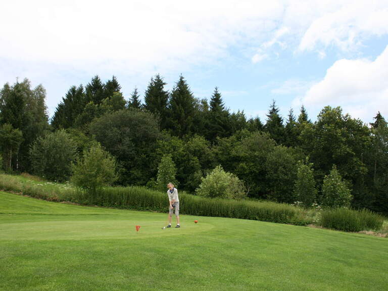 Golfspieler auf Golfplatz umgeben von Bäumen im Bayerischen Wald