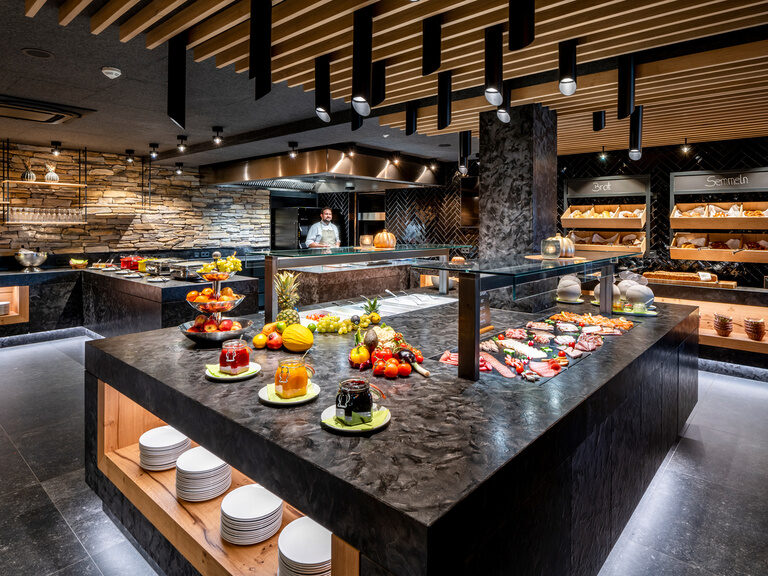 Modernes Frühstücksbuffet mit Bodenbeleuchtung und großer Auswahl an Obst, Brot, Säften