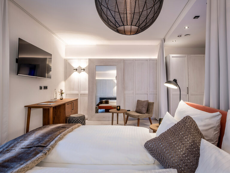 Helles, modernes Zimmer mit Doppelbett, großem Spiegel, Wandbeleuchtung und TV