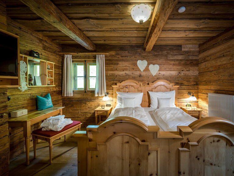 Modernes Badezimmer mit Holzwaschtisch, zwei Waschbecken, beleuchteter Dusche, davor rundes Doppelbett