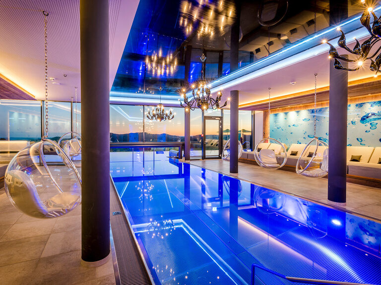 Beleuchteter, blauer Innenpool in der Dämmerung im Hotel Hüttenhof