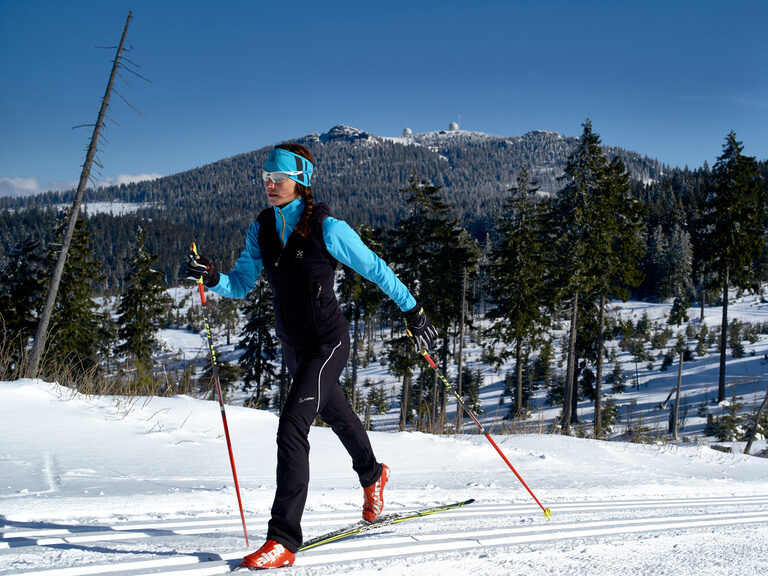 Langläuferin auf schneebedeckten Loipe umgeben von Bäumen im Bayerischen Wald