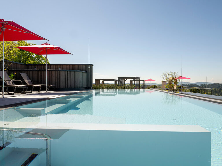 Moderner Dachpool mit Liegen auf Terrasse vom 4-Sterne-Luxushotel Hüttenhof Moderner Dachpool mit Liegen und Sonnenschirmen auf Terrasse mit Blick auf Bayerischen Wald