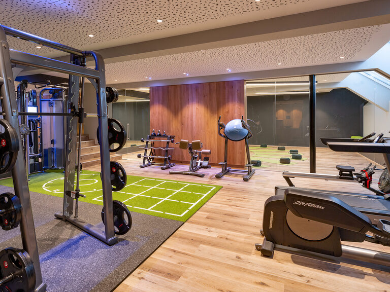 Modern ausgestatteter Fitnessraum mit Glaswand und Trainingsgeräten im Hüttenhof