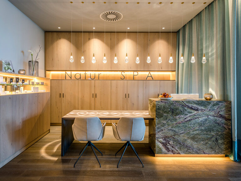 Moderner Beratungsraum mit Schriftzug 'Natur-SPA', Holzregal mit Pflege-Produkten und Beleuchtung