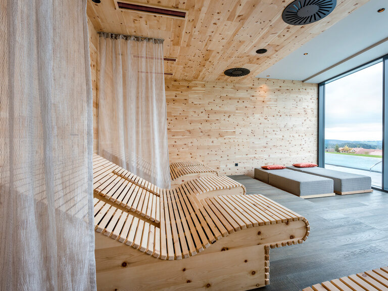Moderner Ruheraum mit Holzliegen, Vorhängen und Panoramablick auf den Bayerischen Wald
