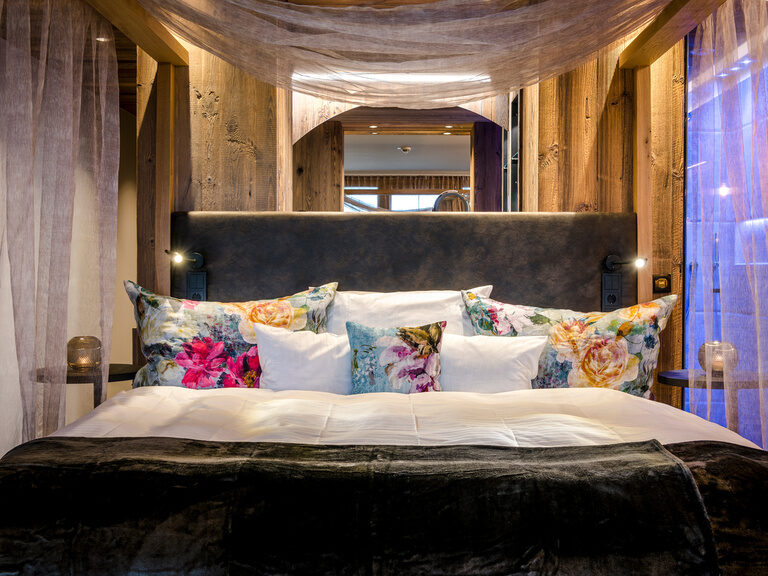 Modernes Bett mit geblümten Kissen im Hotel Hüttenhof