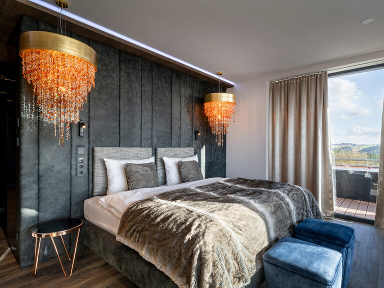 Modernes Doppelzimmer mit Kronleuchtern im Wellnesshotel Hüttenhof Gemütliches Boxspringbett mit Kuscheldecke im Zimmer des 4 Sterne Wellnesshotel Hüttenhof im Bayerischen Wald