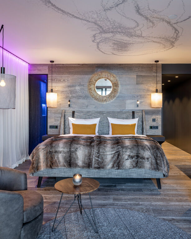 Modernes Luxuszimmer mit grauer Einrichtung und Holzwänden im Wellnesshotel Hüttenhof