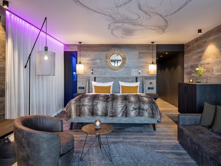 Modernes Luxuszimmer mit grauer Einrichtung und Holzwänden im Wellnesshotel Hüttenhof