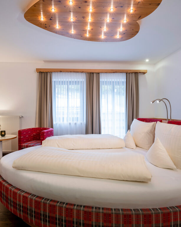Romantisches Zimmer mit rundem Bett und herzförmiger Holzplatte mit Glühbirnen