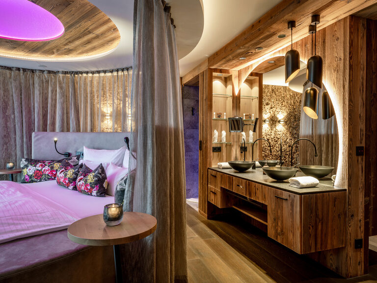 Moderne Suite mit rundem Bett, Holzwaschtisch, runden Waschbecken und beleuchtetem Spiegel