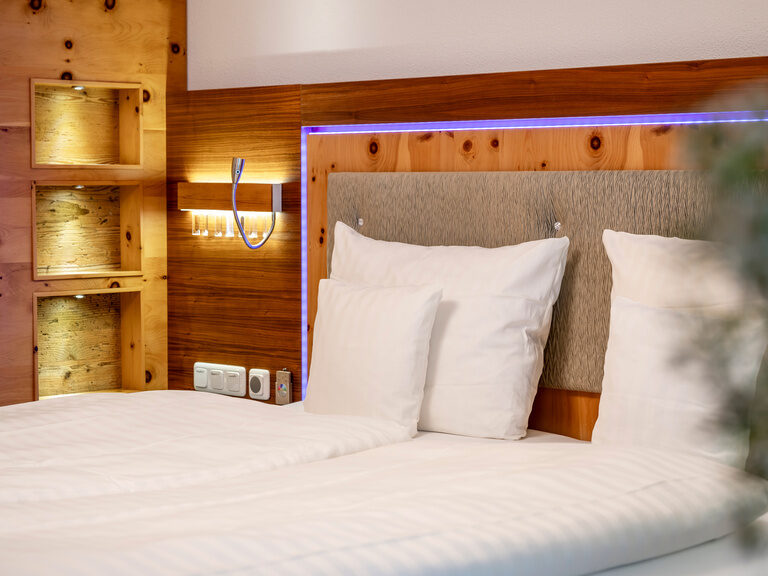 Nahaufnahme modernes Doppelbett aus Holz, umrandet von LED-Beleuchtung