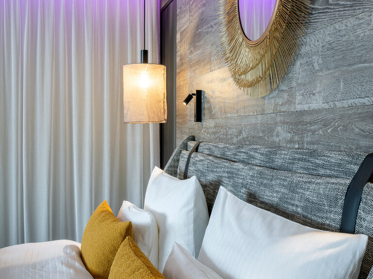 Nahaufnahme von Kissen auf Doppelbett im Luxushotel Hüttenhof Nahaufnahme von aufgereihten Kissen auf Doppelbett, darüber goldener runder Spiegel