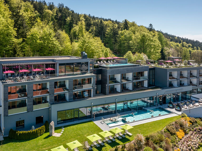 Rückenansicht von Paar im Bademantel, das Sonne auf Terrasse vom Hotel genießt