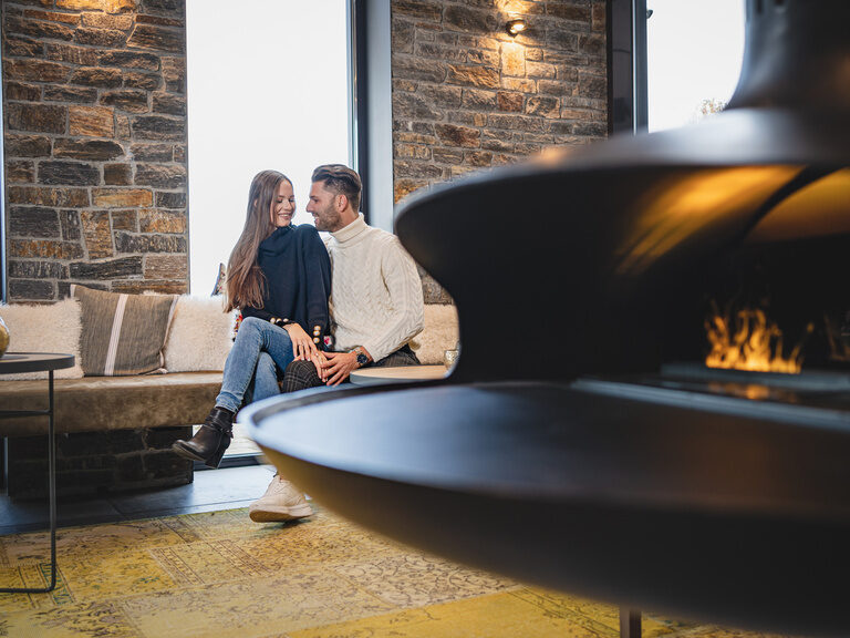 Lachendes Paar auf Sofa in Eingangsbereich im Hüttenhof