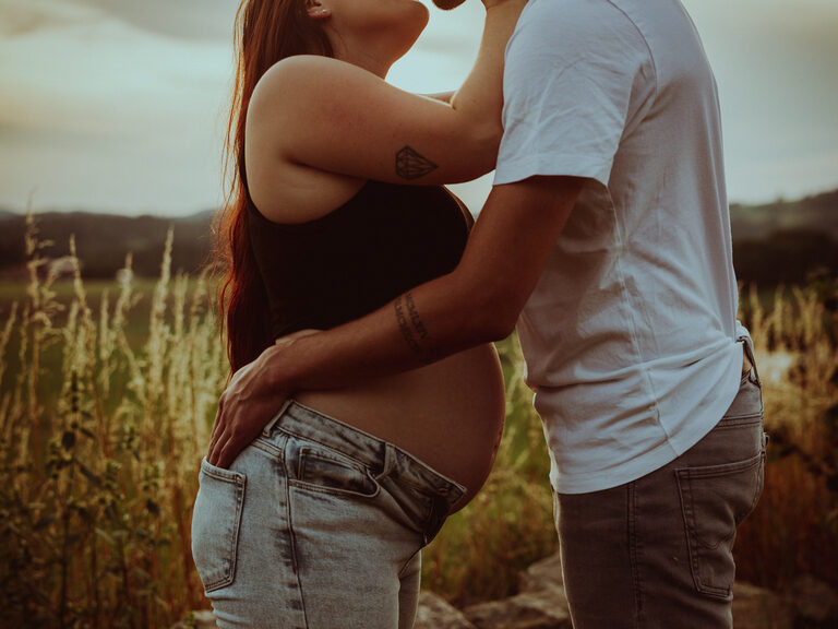 Paar küsst sich auf Terrasse von Holzhütte nahe dem Luxushotel Hüttenhof Liebespaar sitzt auf auf der Terrasse von idyllischen Holzhütte bei einem Kuss